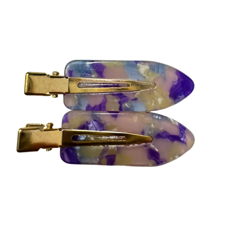 Two hair claw clips with gold-tone metal hardware and translucent resin inserts featuring a marbled pattern of purple, light blue, and cream, displayed on a solid white background.