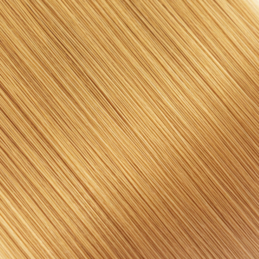 A close-up texture swatch of straight, fine hair in a warm golden blonde shade, filling the entire frame.
