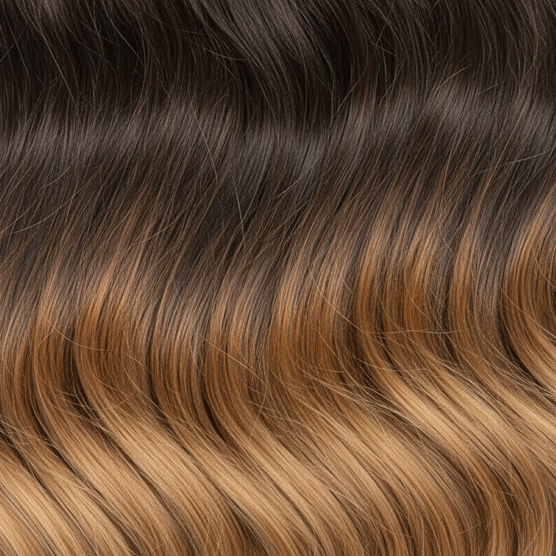 A close-up swatch of hair showing a dark brown to warm golden-brown ombré gradient.