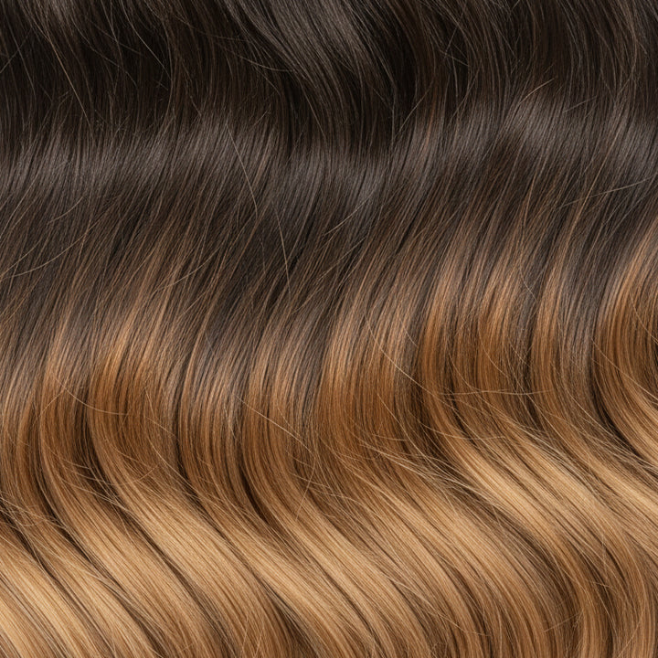A close-up swatch of hair showing a dark brown to warm golden-brown ombré gradient.